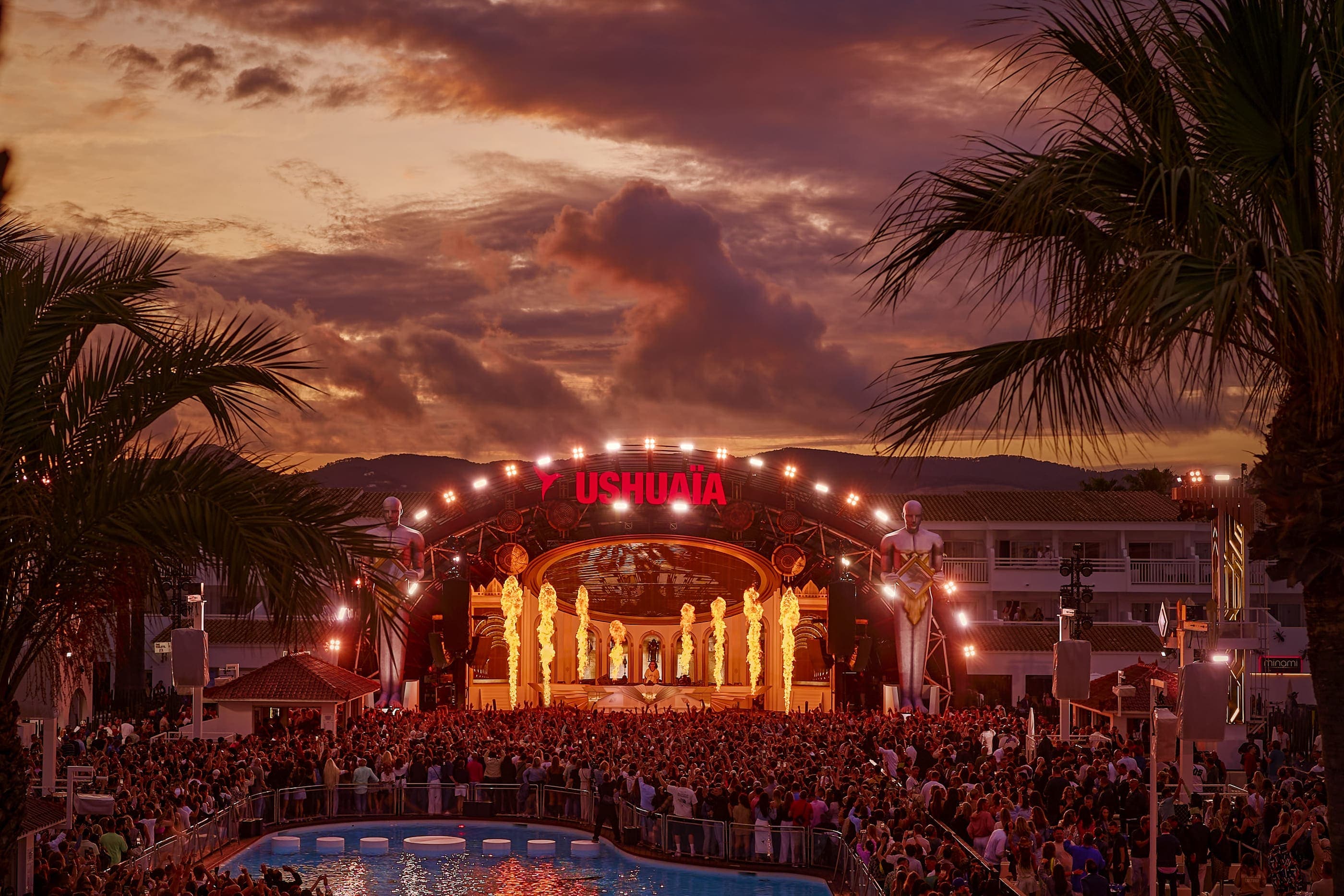 Ushuaïa Ibiza during a Tomorrowland residency, with a packed open-air crowd dancing at sunset and large-scale stage production